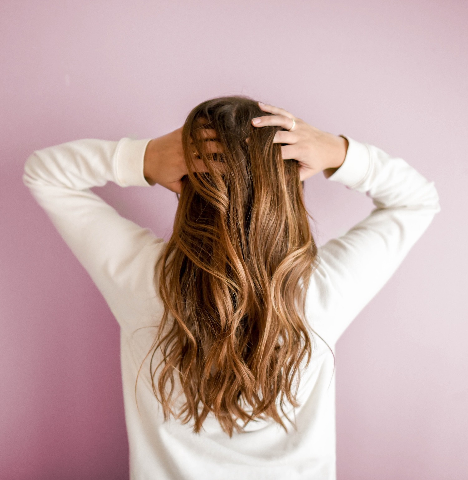 caucasian woman grabbing scalp with both hands and worrying about hair loss