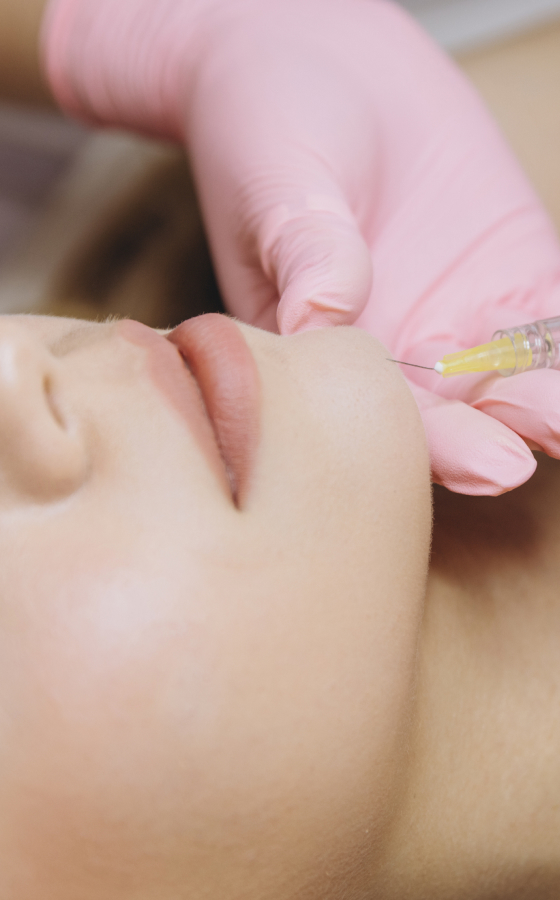 Doctor performing hyaluronic acid-based injectable treatment on a patient in clinic