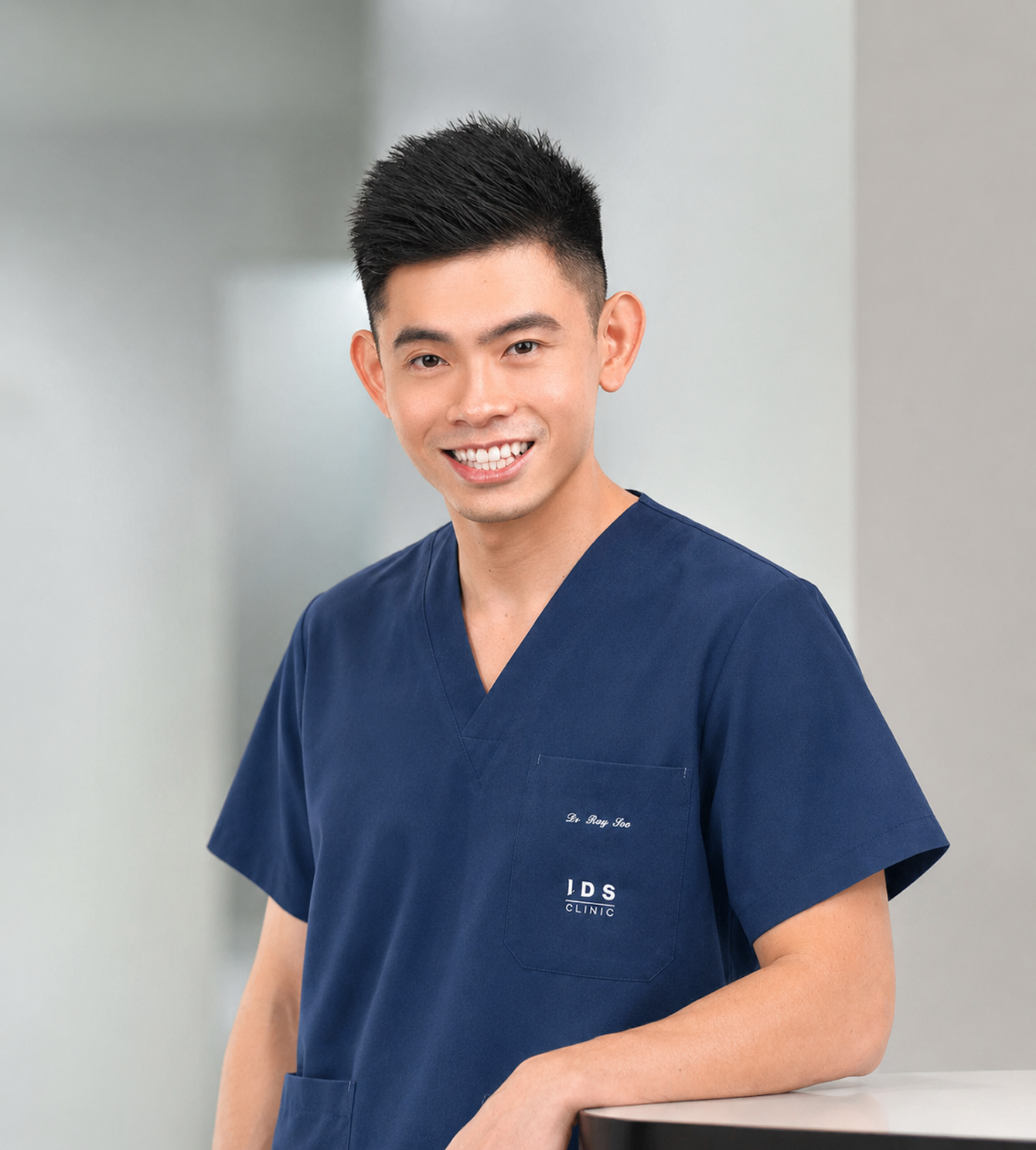 A doctor in navy scrubs with the IDS Clinic logo standing in a modern clinic setting.