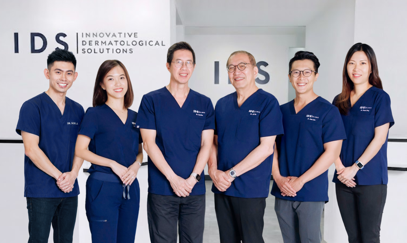 A professional dermatology team standing together in front of the IDS Clinic logo.