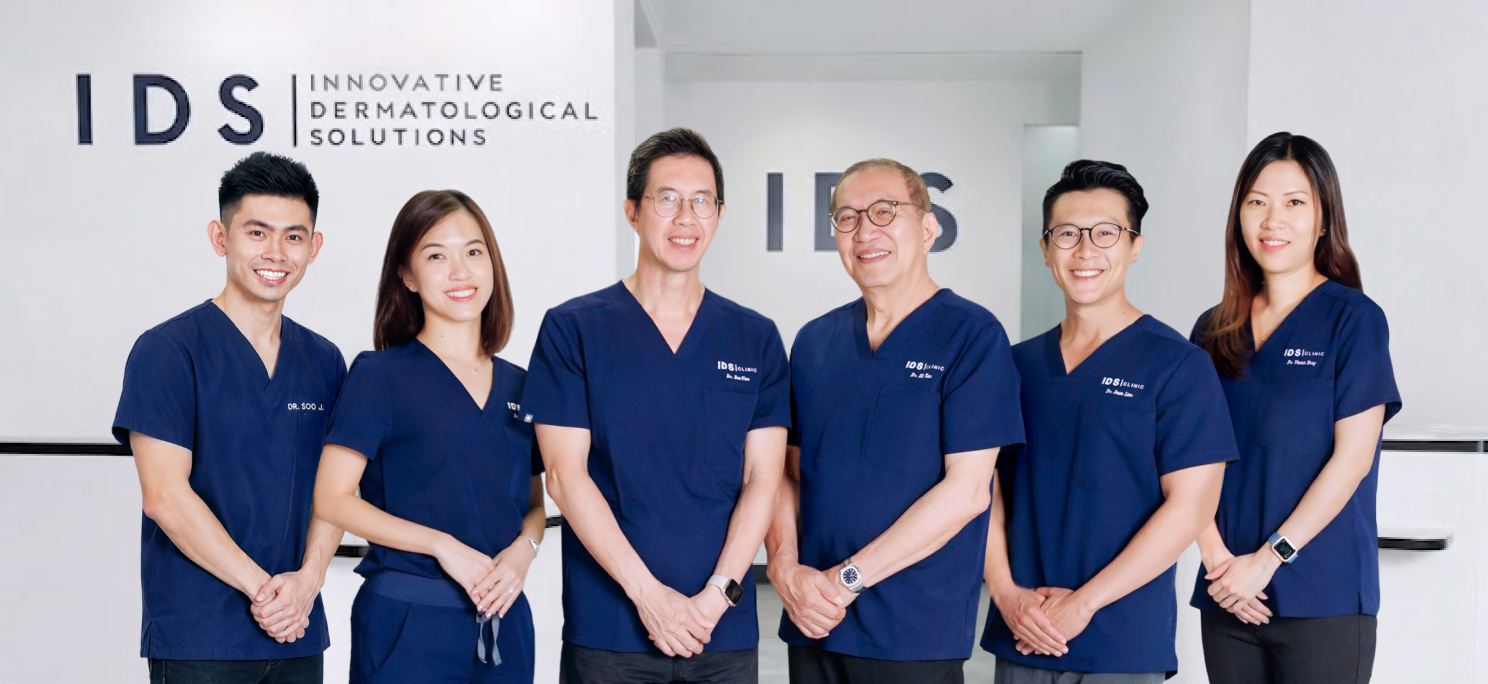 A group of five dermatology professionals standing together in front of the IDS Clinic logo.